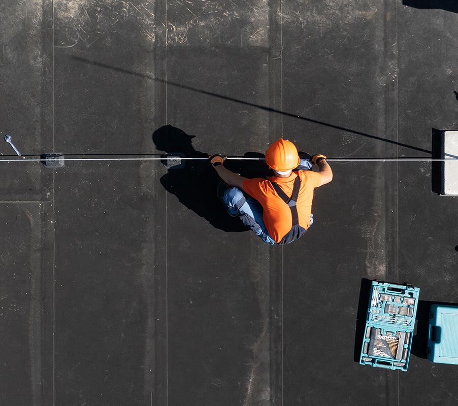 Contractor evaluating preparation for silicone coating over an asphalt roof